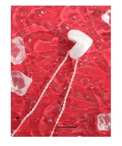 Macro shot of matte silver heart necklace on red water surface with ice props