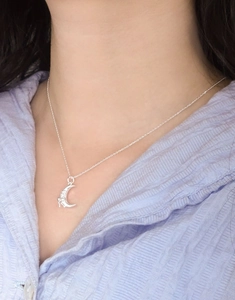 Close-up of S925 sterling silver crescent moon necklace with bow pendant on a model