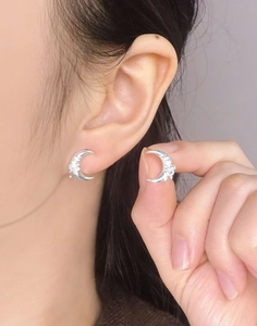 Detail of silver crescent moon stud earrings with delicate bow design on ear