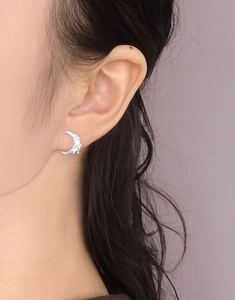 Close-up of minimalist silver crescent moon stud earring worn on model earlobe