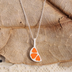 S925 sterling silver necklace with orange heart enamel slice pendant on dry leaf background