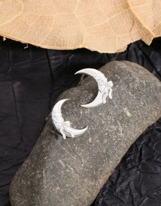 Macro detail of S925 sterling silver crescent moon earrings with bow relief on a stone