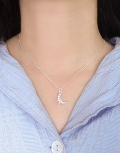 Close-up of S925 sterling silver moon pendant necklace worn by a female model