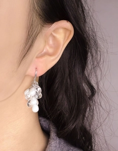 Gros plan de boucles d'oreilles en grappe de perles blanches et perles transparentes