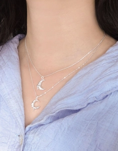 Macro view of a double-layered S925 silver necklace with textured moon pendants on a model