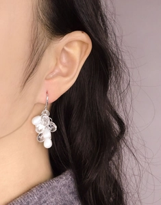 Détail de boucles d'oreilles grappe en perles et cristaux portées pour style chic