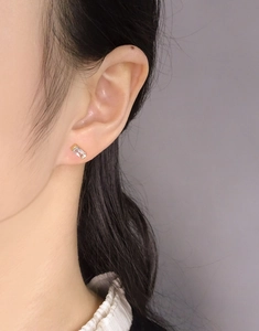 Close-up of minimalist S925 silver rectangle baguette cut stud earrings on ear