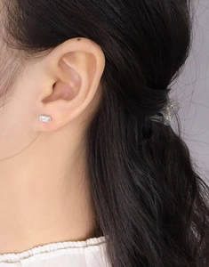 Macro shot of S925 silver stud earring with a rectangular clear zircon on ear lobe