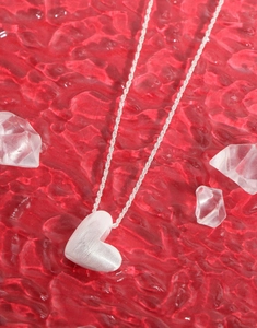 Close-up of S925 sterling silver heart necklace with brushed matte finish on red silk