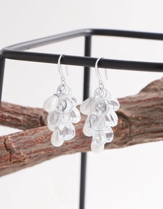 Détail de boucles d'oreilles en argent avec perles en grappe de raisin sur une branche