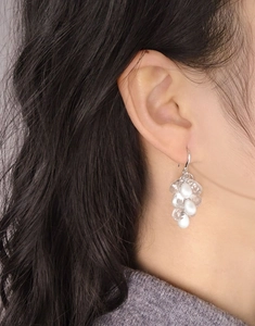 Gros plan sur des boucles d'oreilles en argent S925 avec perles blanches et raisins clairs