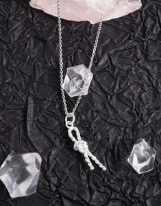 Detailed close-up of a S925 sterling silver twisted knot pendant on a textured dark surface
