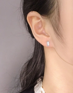 Macro detail of silver rectangular zircon stud earring shown on a model's ear