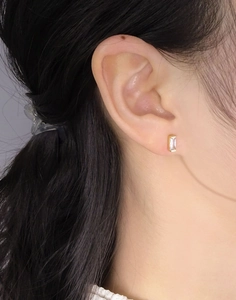 Detail of elegant gold rectangle zircon stud earring worn on model's ear for daily style