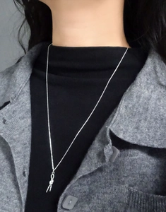 Close-up of a silver S925 knotted rope pendant necklace worn over a black turtleneck