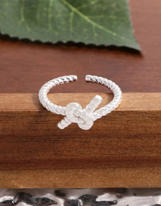 Detailed macro shot of a twisted knot open ring in S925 silver on a wooden stand