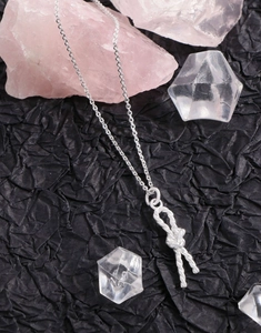 Macro detail of S925 sterling silver rope knot pendant on black textured surface