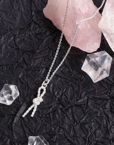 Macro shot of silver S925 knotted rope necklace pendant on textured black background