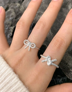 Close-up of S925 sterling silver braided knot and bow open rings worn on fingers