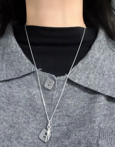 Detail of S925 sterling silver knotted pendant necklace on a grey sweater