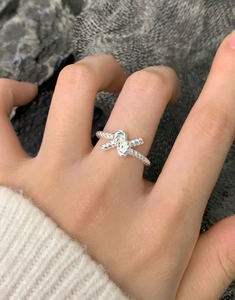 Close-up of S925 sterling silver twisted knot ring worn on hand with white sweater