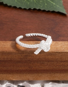 Macro detail of S925 sterling silver knotted twist open ring on a wooden surface