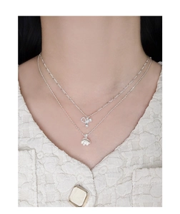 Dettaglio di una collana a due strati in argento S925 con ciondoli a cuore e fiore