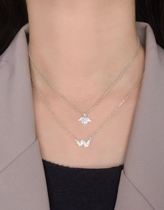 Detail of S925 silver layered necklace with heart zircon and woven butterfly pendants