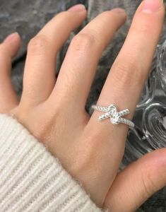 Close-up of S925 sterling silver twisted knot ring worn on finger with a cozy sweater
