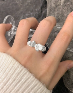 Gros plan d'une bague nœud en argent S925 avec texture plissée portée au doigt