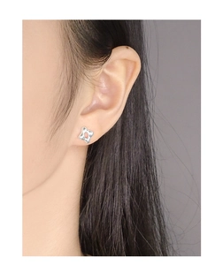 Gros plan d'un clou d'oreille étoile évidé en argent S925 porté sur l'oreille