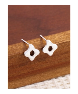 Détail des boucles d'oreilles étoiles évidées en argent S925 sur support en bois