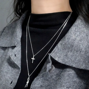 Layered S925 sterling silver necklace with cross and twisted knot pendants on a model