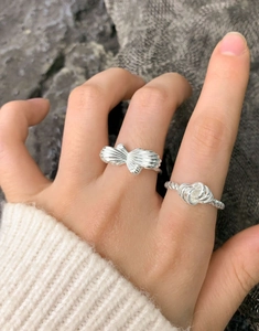Detailed view of S925 sterling silver twist knot and radiant bow rings on model finger