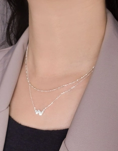Detail of layered S925 silver necklace with double-layer butterfly pendant on a model