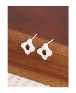 Vue macro des boucles d'oreilles étoiles évidées en argent S925 sur support en bois