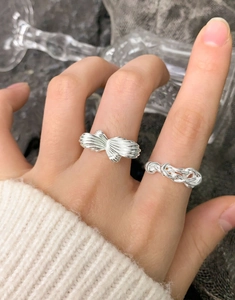 Detail of S925 sterling silver layered rings with irregular cross wrap design on a hand