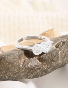 Detail of S925 sterling silver multi-layer knotted open ring on a natural stone background