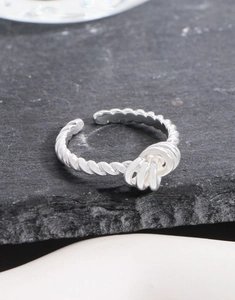 Detailed view of S925 sterling silver twisted ring with interlaced knot on stone slab