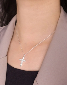 Close-up of S925 silver cross necklace with clear cubic zirconia on female model neck