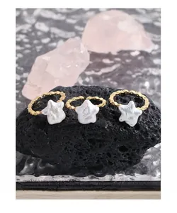 Détail de trois bagues dorées avec perles en forme d'étoile et textures sur pierre