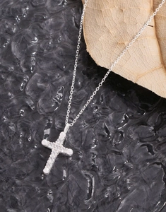 Macro shot of silver cross necklace pendant featuring inlaid cubic zirconia on a chain