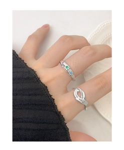 Macro shot of silver textured ring with colored stones and a minimalist knot ring design