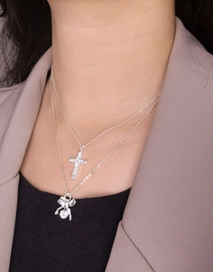 Detail of layered S925 silver necklace with zircon cross and bowknot pendants