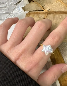 Détail macro de bague étoile en argent S925 avec perle baroque sur main de femme