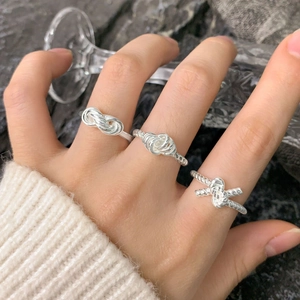 Three-piece set of S925 silver layered knot rings shown on a hand with premium stone backdrop