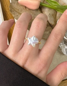 Détail d'une bague étoile en perle baroque irrégulière avec petits diamants sur anneau doré