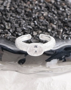 Macro shot of oval zircon stone on a hammered silver ring band with textured details