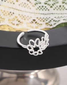 Detailed view of silver hollow floral ring featuring intricate open petals on a black stand
