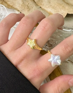Gros plan sur bague étoile en argent S925 et bague perle baroque portées avec élégance